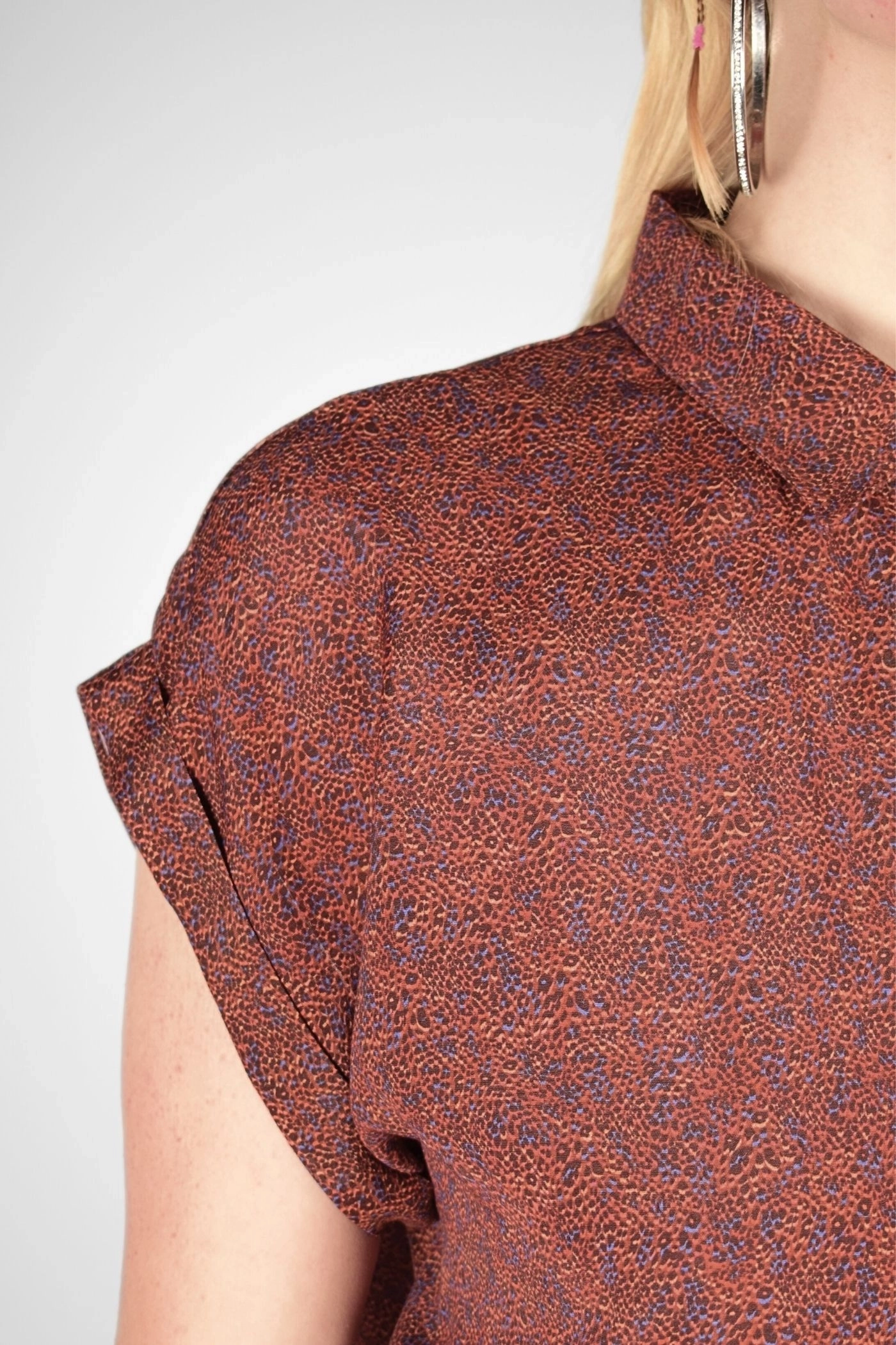 Detailansicht des umgeschlagenen Ärmels und Kragens der Bluse in orange/rot gemustert