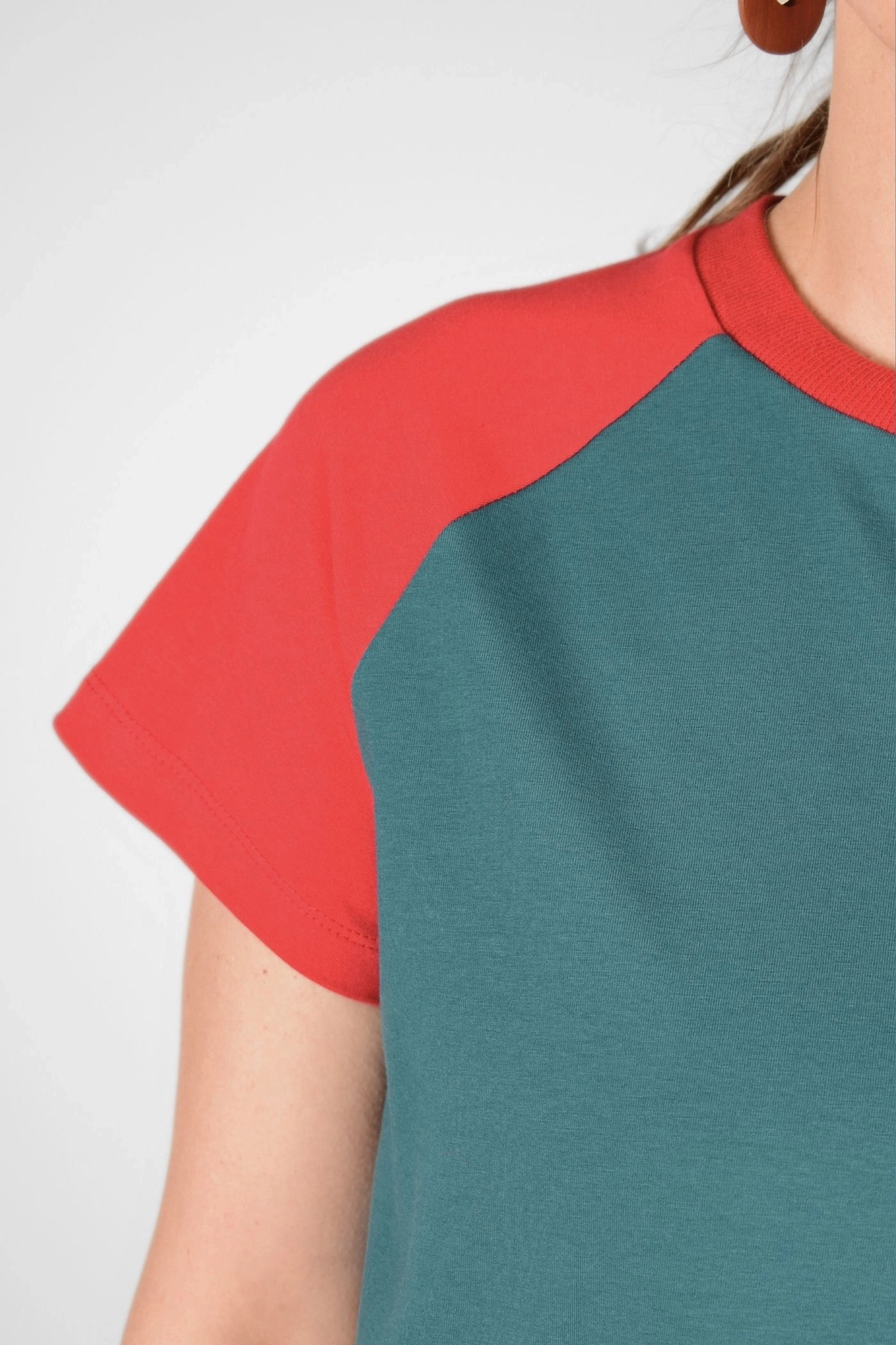 Detailansicht von T-Shirt "Sista" im Raclan Schnitt petrol und rot