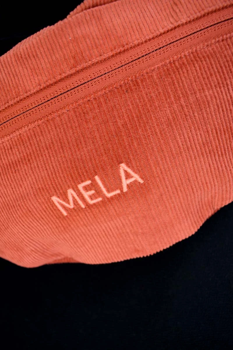 Mela Gürteltasche Cord Rotbraun Detailaufnahme Label-Stickerei