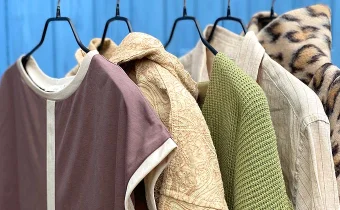 Kleidungsstücke in gedeckten Farben an Kleiderbügeln hängend aufgereiht